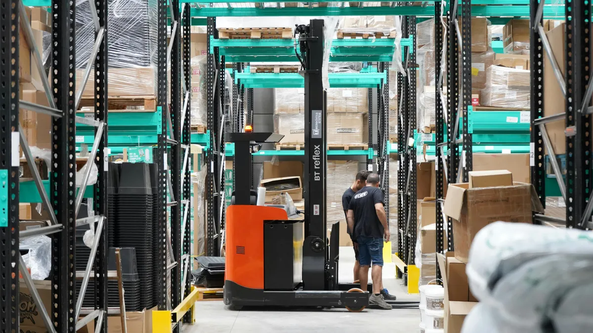 Reachtruck aan het werk in een magazijn met hoge stellingen
